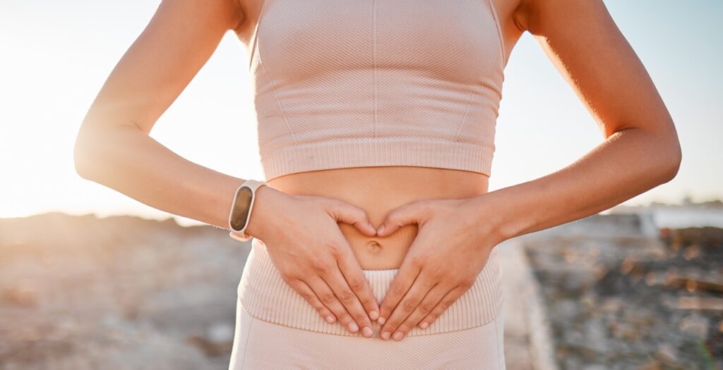 Photo of woman with her heart shaped hands on stomach for fitness, weight loss diet or holistic gut.