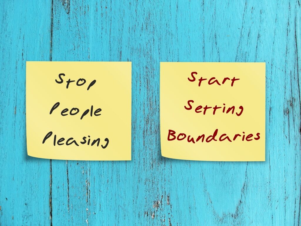 Two notes stick on blue wood background STOP PEOPLE PLEASING - START SETTING BOUNDARIES