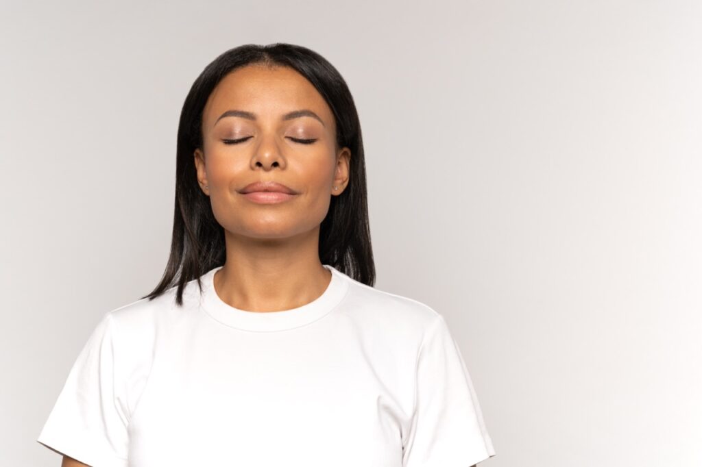 Black woman practicing deep breathing techniques.
