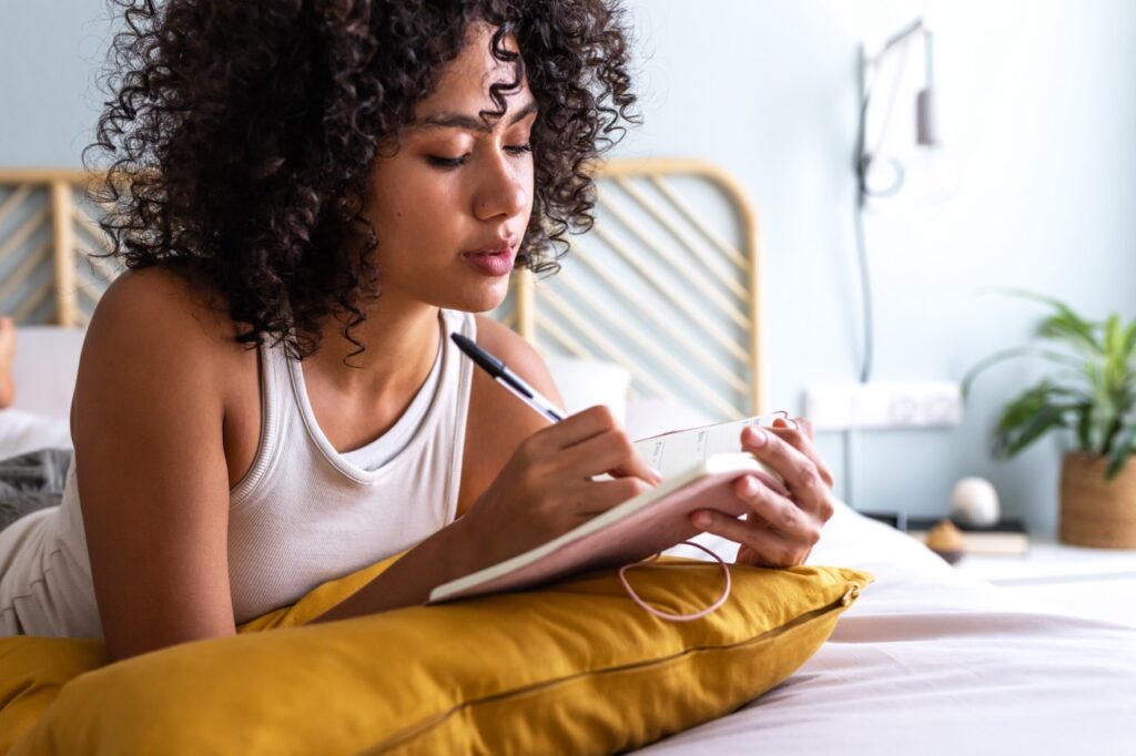 Young multiracial woman writing in journal.