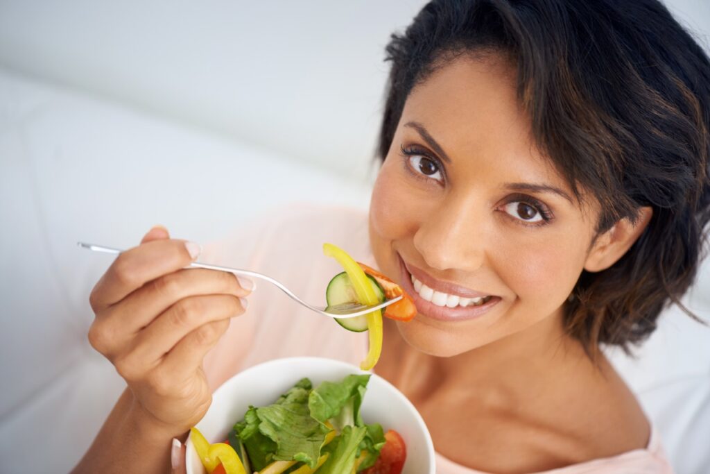 A pretty young woman enjoying a healthy salad.