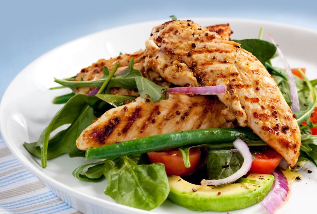 Salad of grilled chicken tenderloins with avocado, tomatoes, red onion, green beans, spinach and arugula.