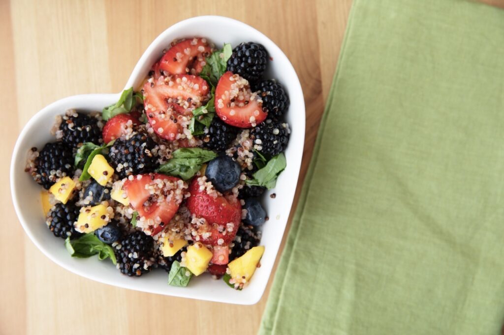 Healthy quinoa fruit salad in heart shaped bowl.