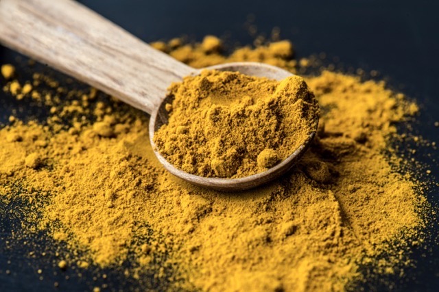 Closeup of tumeric powder spice on a spoon.