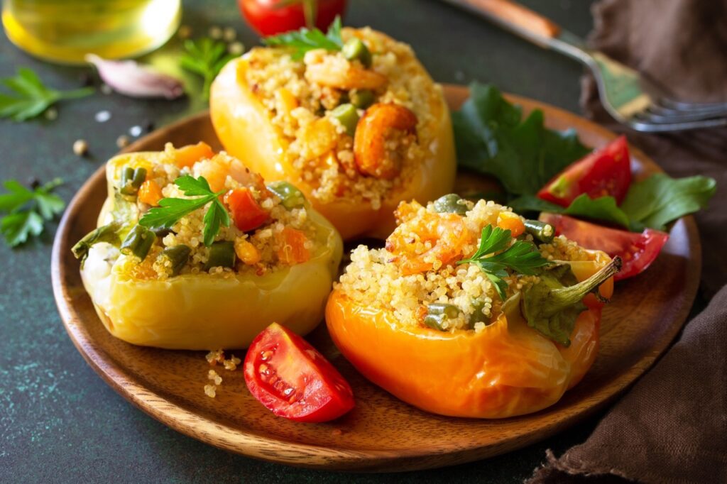 Vegetarian dish. Peppers stuffed with quinoa, shrimp  and vegetables on dark stone table.