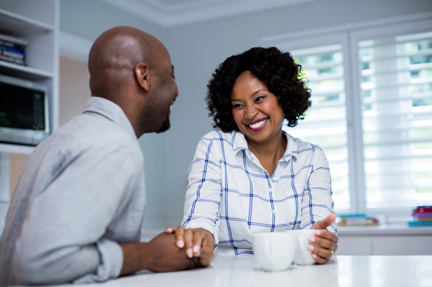 A man and woman holding hands at the breakfast table.
