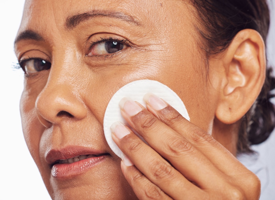 Mature woman gently cleansing her face with a cotton pad, demonstrating a gentle skincare routine for menopausal skin