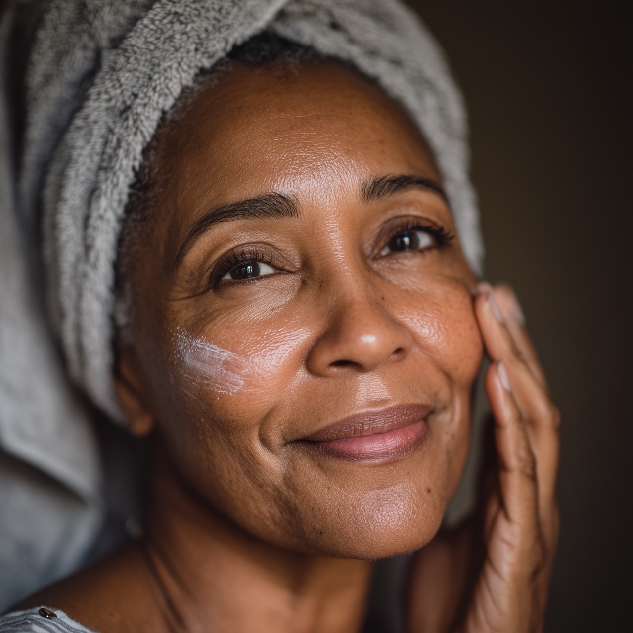 Mature Black woman applying exfoliating product to her face, illustrating gentle skincare practices for healthy menopausal skin